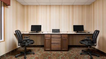 A room with a desk, two chairs, and two monitors.