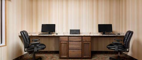 Una habitación con un escritorio, dos sillas y dos monitores.