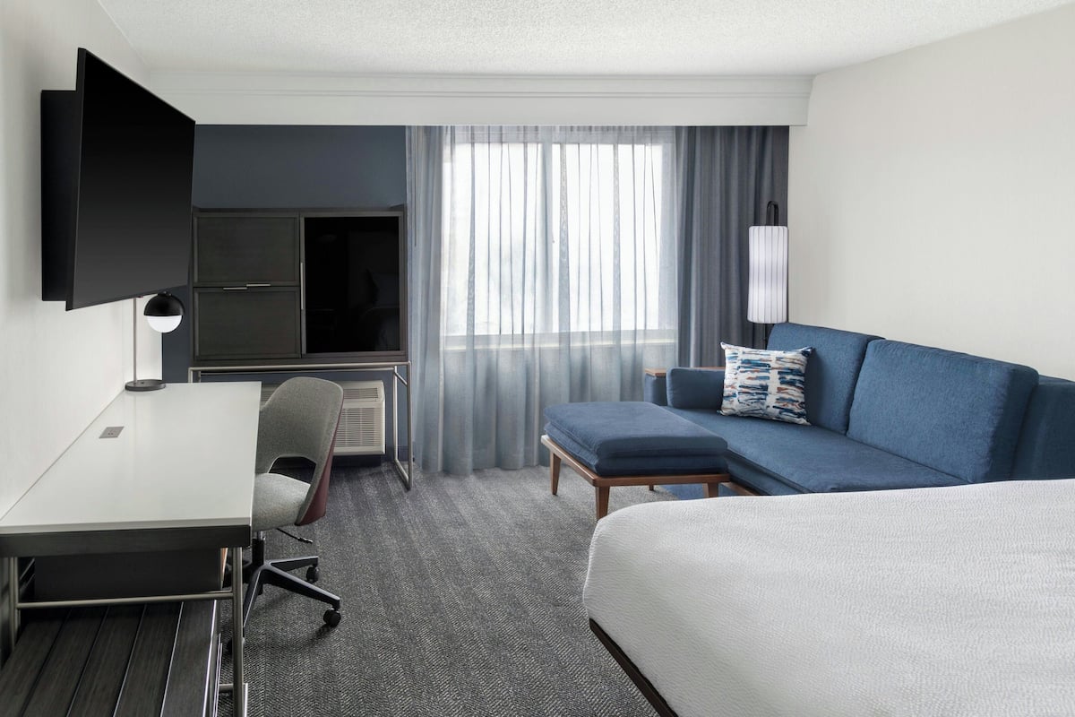 Een hotelkamer met een bed, een bureau, een stoel, een televisie en een bank.