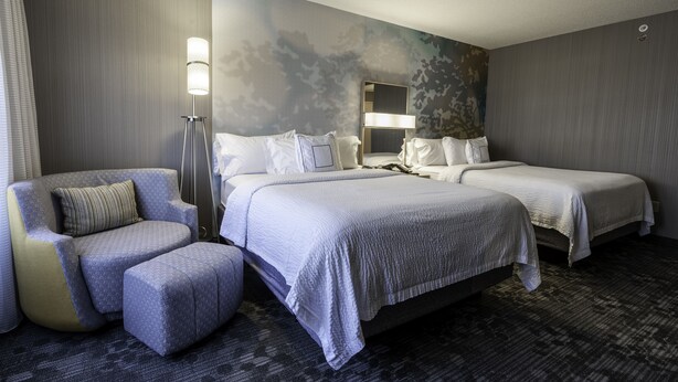 Ein Hotelzimmer mit zwei Betten, einem Sofa, einem Sessel und einem großen Spiegel.