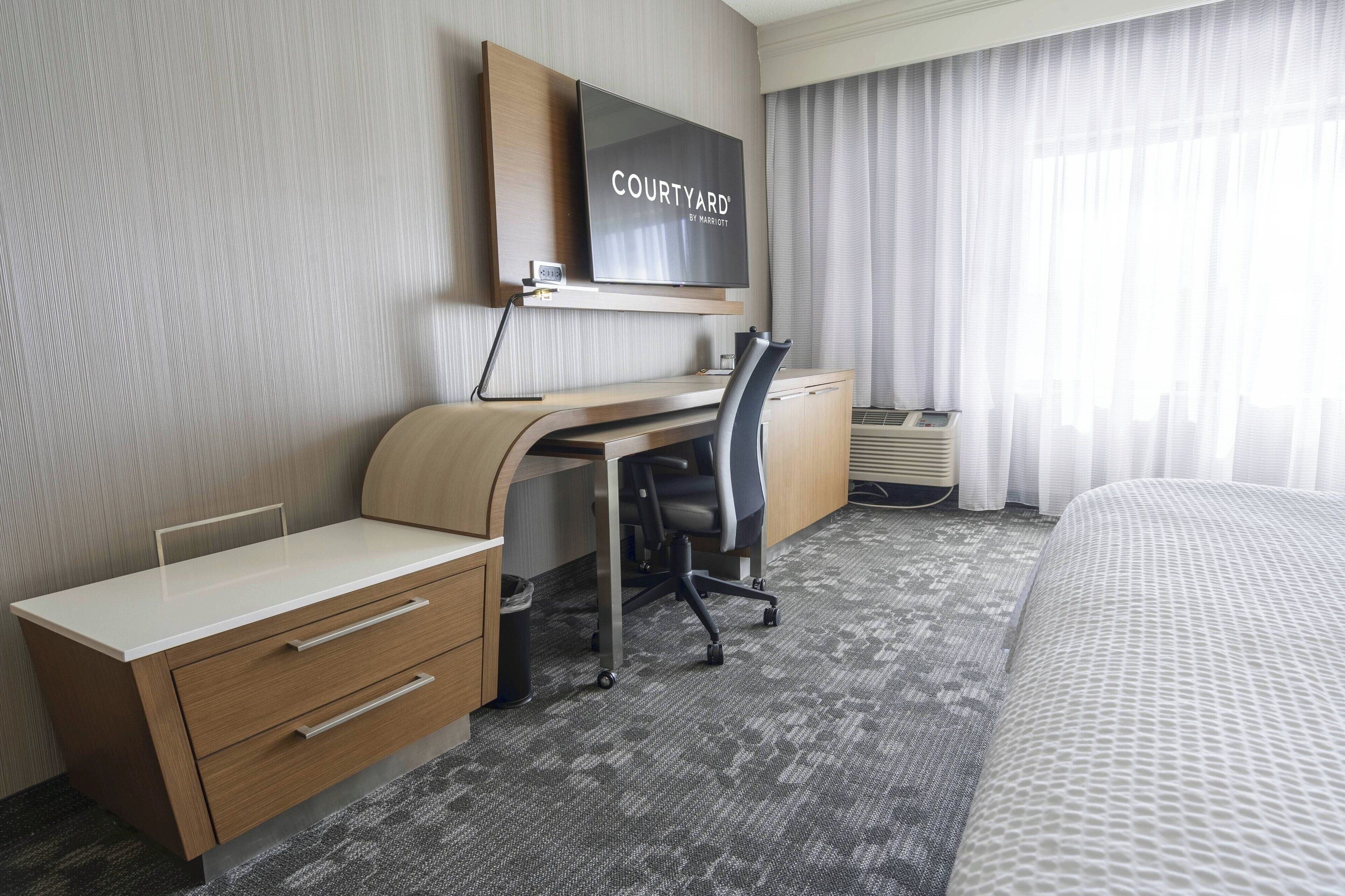 A hotel room with a desk, chair, and bed.