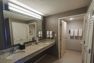 Un baño moderno con dos lavamanos, un espejo grande y una puerta que da a un área de aseo.