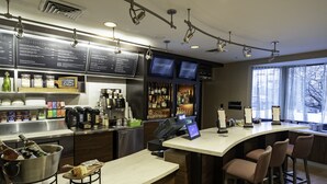 Ein moderner Barbereich mit digitaler Speisekarte, Barhocker und einer Kaffeestation.