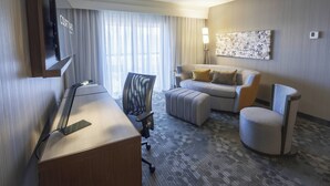 Ein Hotelzimmer mit Schreibtisch, Stuhl, Sofa und Ohrensessel.