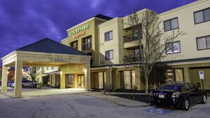 Ein Courtyard by Marriott Hotel mit überdachter Einfahrt, einem Parkplatz und einem schwarzen Auto davor.