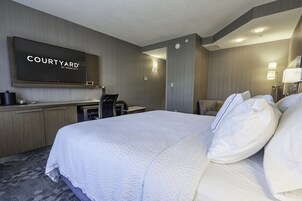 Una habitación de hotel con una cama grande, un escritorio, un televisor de pantalla plana y una zona de estar.