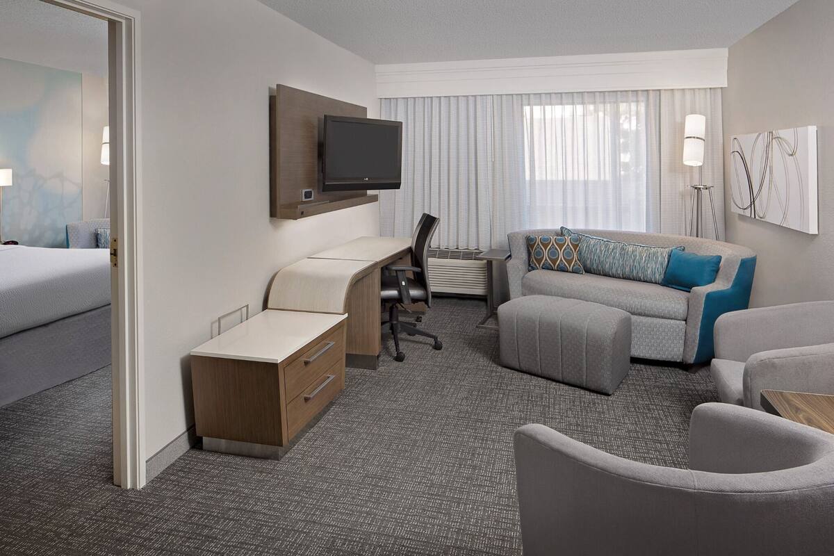 A hotel room with a bed, a desk, a sofa, and a TV.