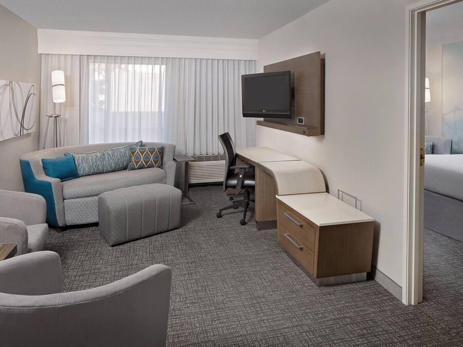 Una habitación de hotel con sofá, escritorio, silla, televisión y cama.