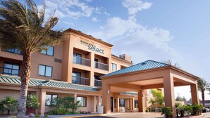 Un hotel Sonesta Select con ingresso coperto, diversi balconi e palme.