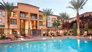 Un hotel con piscina, diversi balconi e palme.