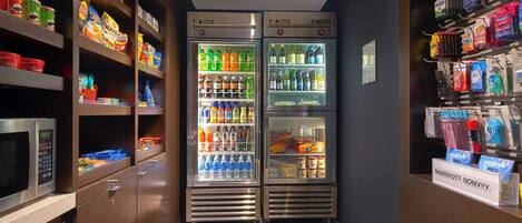 A kitchenette with a microwave, two beverage dispensers, and a variety of snacks and condiments.