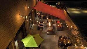 An outdoor patio area with tables and chairs, string lights, and umbrellas. - Courtyard Portland Downtown/Convention Center (Portland)