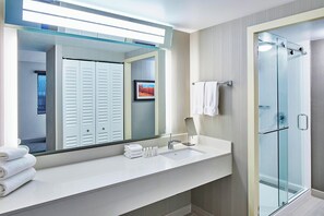 Een moderne badkamer met een grote spiegel, een wit wastafelmeubel en een douchecabine met glazen wanden.