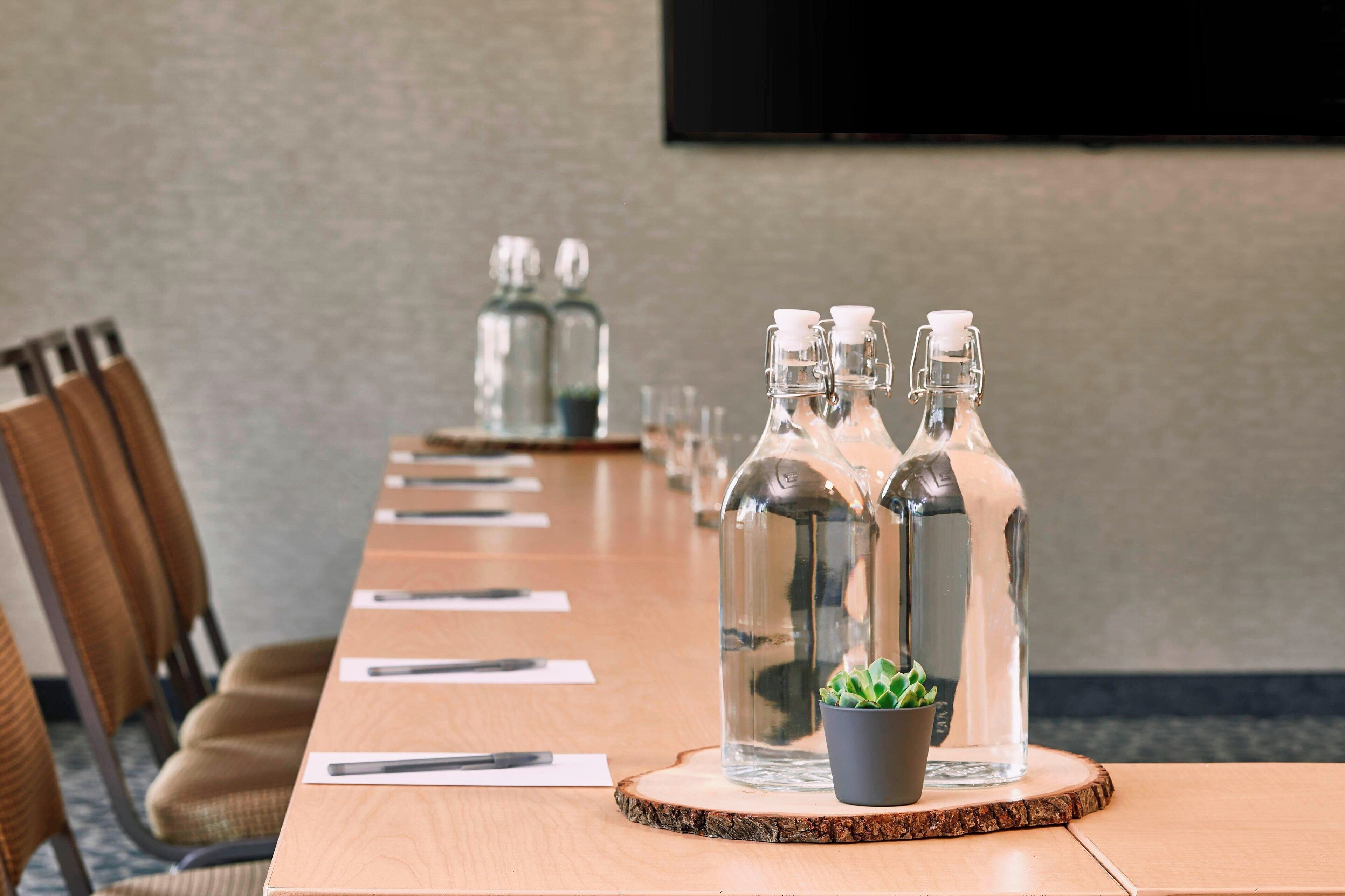 Une salle de conférence avec une longue table, des chaises et une petite plante en pot.