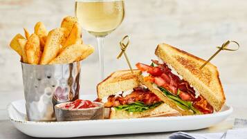 Ein Teller mit einem gegrillten Sandwich, einem Glas Weißwein und einer kleinen Ketchup-Flasche.