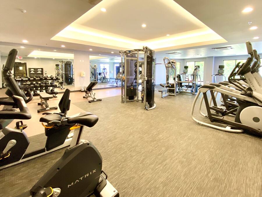 Un gimnasio con varios equipos de ejercicio, entre ellos cintas de correr y máquinas de pesas.