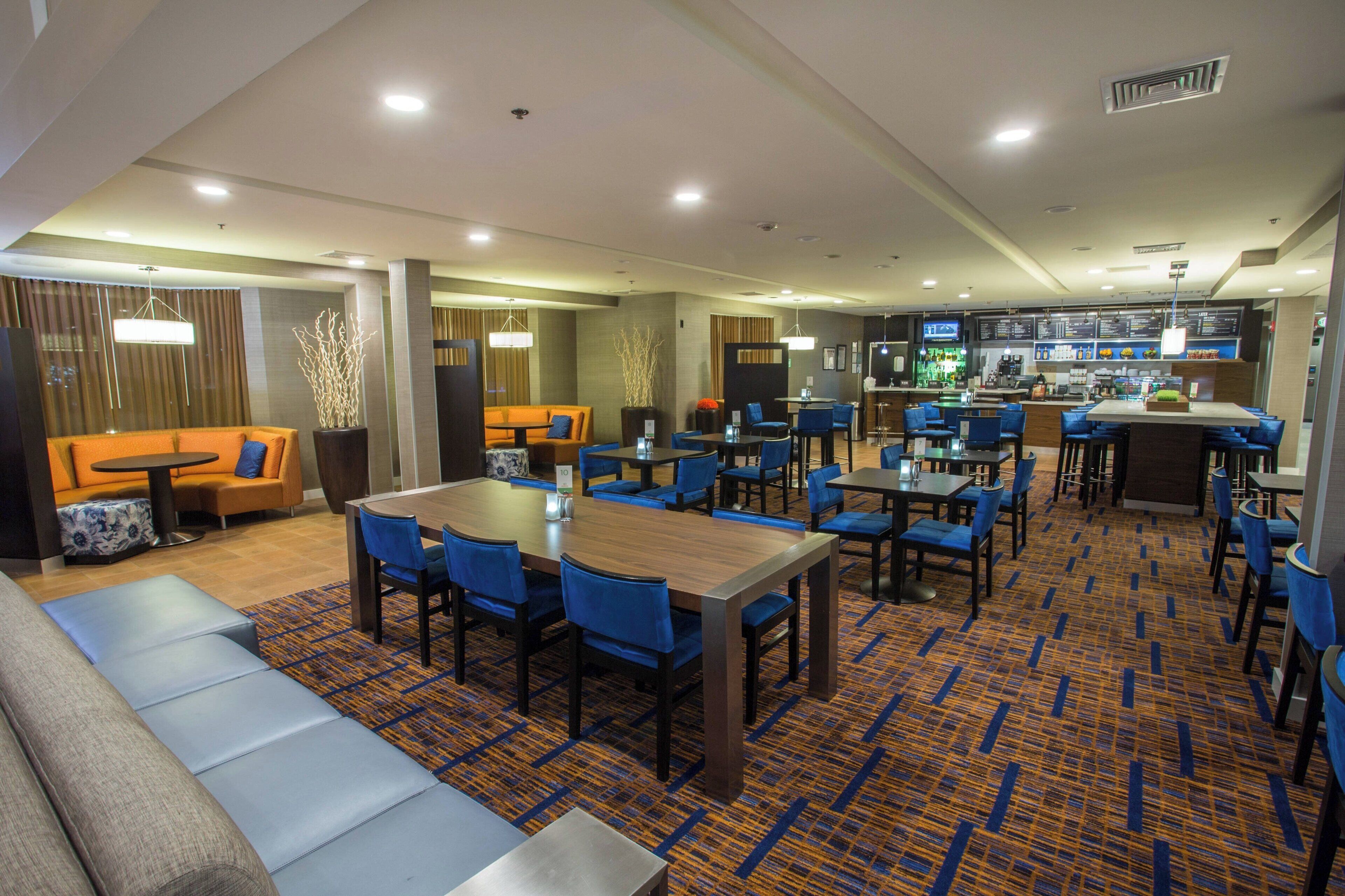 Un vestíbulo de hotel con zonas de estar, un bar y un comedor.