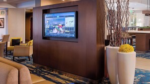 A lobby with a large screen displaying a booking interface, seating area with chairs, and decorative elements. - Courtyard by Marriott North Seattle/Lynnwood (Lynnwood)