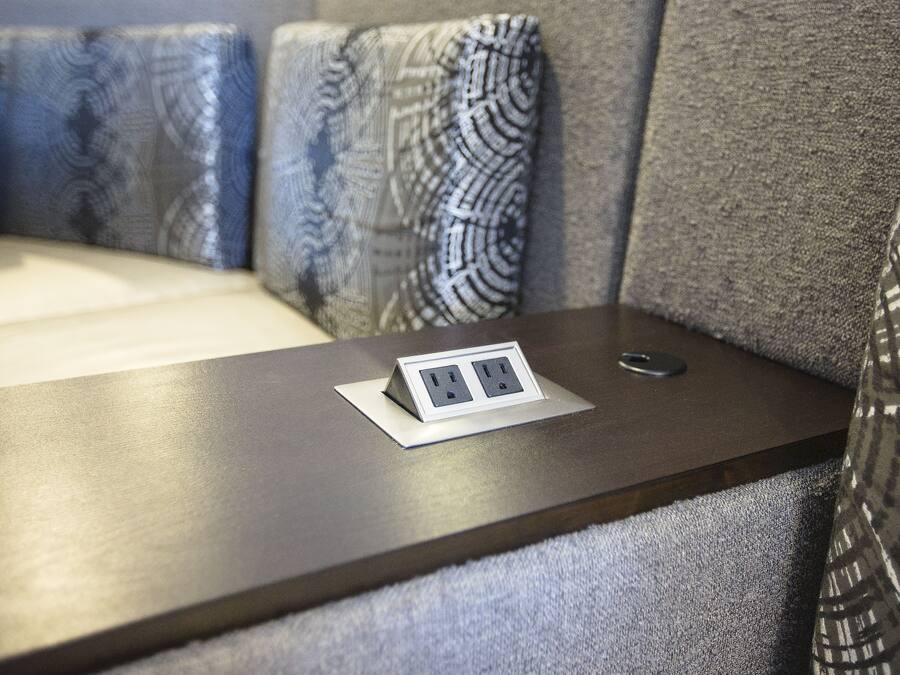 Une petite table équipée d’une prise électrique et d’une télécommande.
