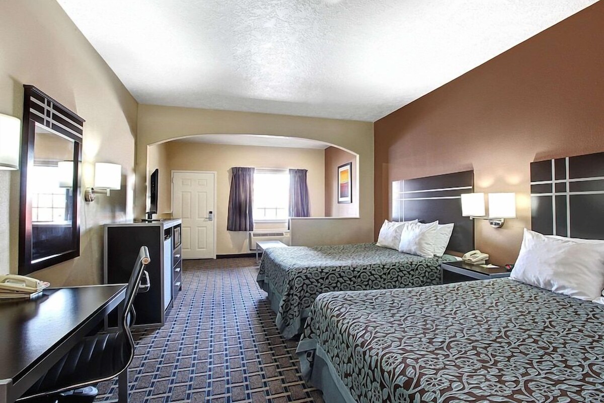 Une chambre d’hôtel avec deux lits, un bureau, une chaise, une commode et une porte.