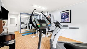 A gym with a treadmill, elliptical, and weight machines.