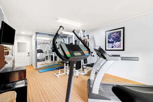 Un gimnasio con cinta de correr, elíptica y máquinas de pesas.