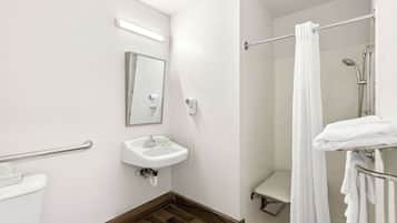 A bathroom with a white sink, a mirror, a shower with a glass door, and a towel rack.