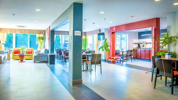 A spacious lobby with a dining area, a kitchen, and a breakfast sign.