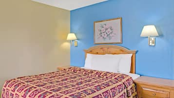 Un dormitorio con una cama, dos lámparas de noche, una mesita de noche y una obra de arte floral enmarcada en la pared.