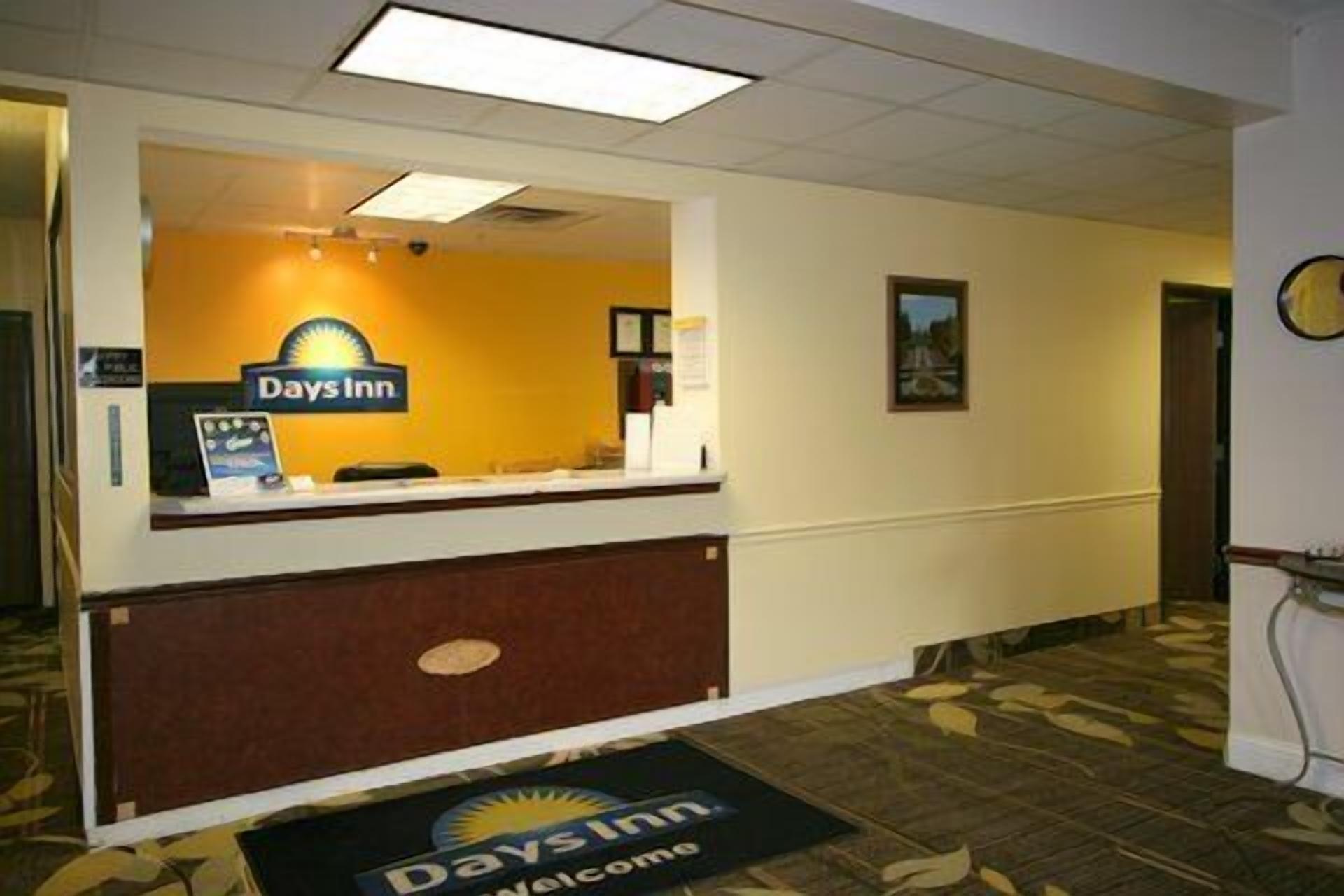 A reception area with a Days Inn sign, a reception desk, and a welcome mat.