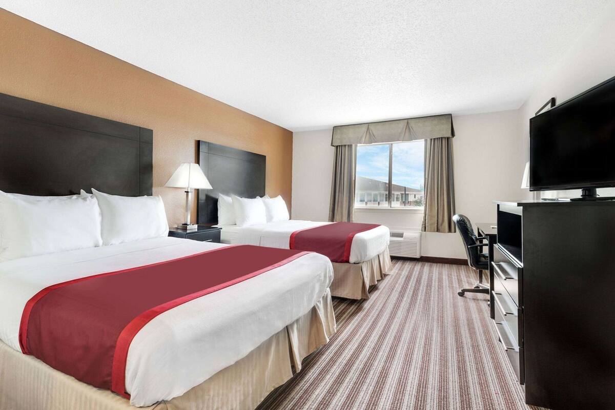Een hotelkamer met twee bedden, een televisie, een bureau en een raam met gordijnen.