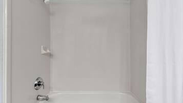 A bathroom with a bathtub, a showerhead, and a white curtain.