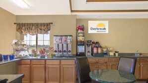 A breakfast area with a coffee machine, vending machines, and a Daybreak sign.