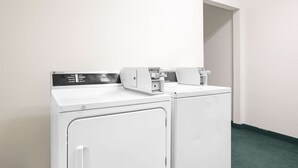 A laundry area with two white washing machines and a control panel.