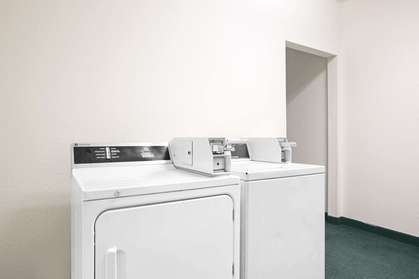 Un espace buanderie équipé de deux machines à laver blanches et d’un panneau de commande.
