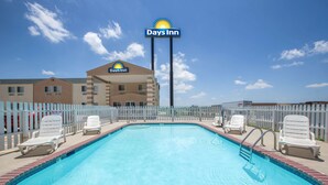 A Days Inn with a swimming pool, white chairs, and a fenced area.