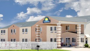 A Days Inn building with a white picket fence in front, multiple windows, and a clear sky.