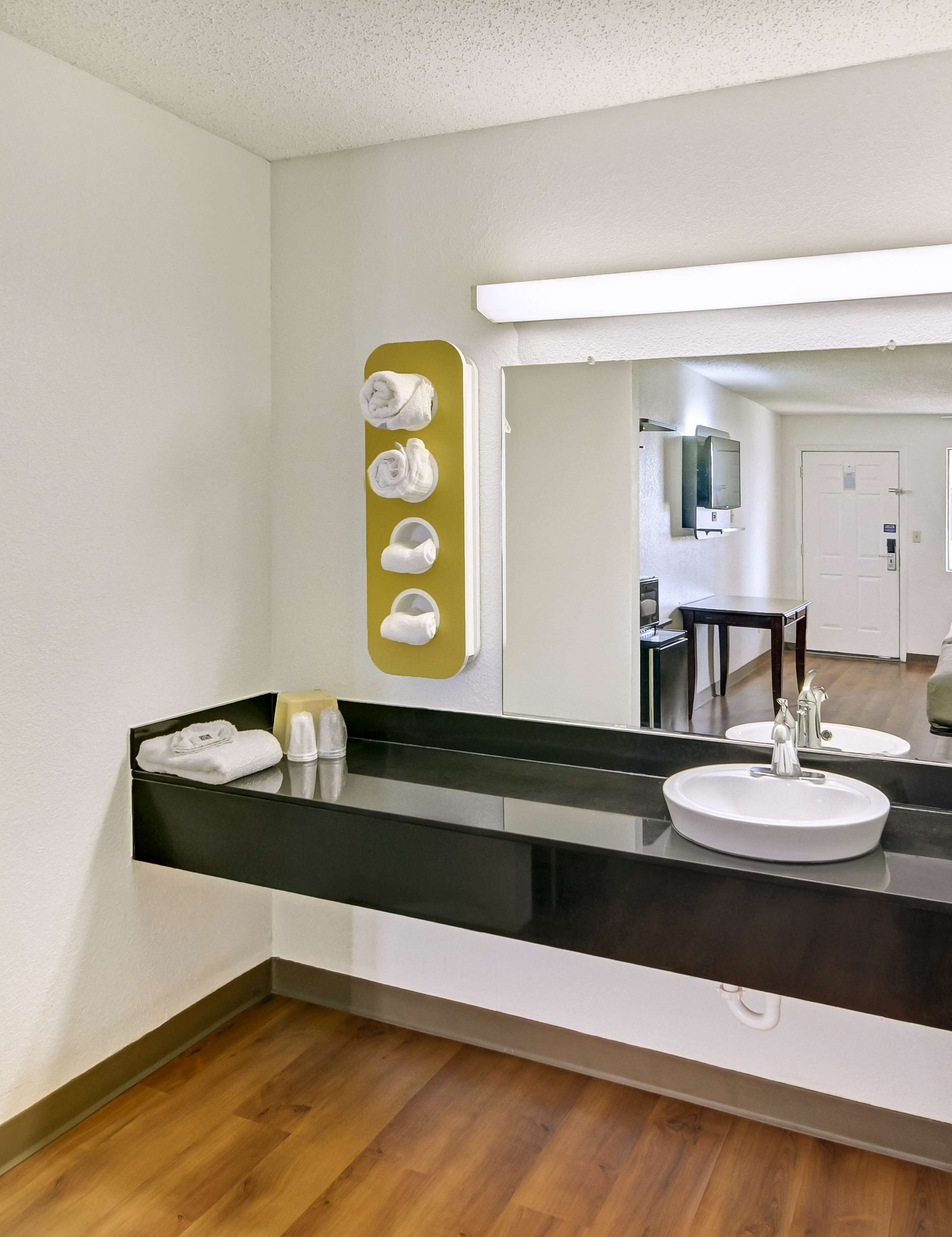 Een moderne badkamer met een zwart aanrecht, twee wasbakken, een spiegel en een handdoekrek met vier handdoeken.
