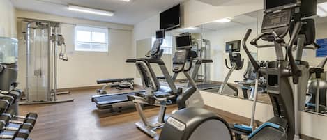 A gym with exercise equipment, a water dispenser, and a mirror.