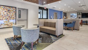 A modern lounge area with a patterned wall, a sofa, chairs, and a small table. - Holiday Inn Express Jonestown - Ft. Indiantown Gap by IHG (Jonestown)