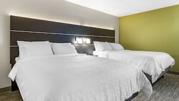 A hotel room with two beds, a modern headboard, and a nightstand with a lamp.