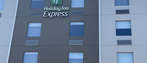 A Holiday Inn Express building facade with a modern design, featuring multiple windows and a prominent green logo.
