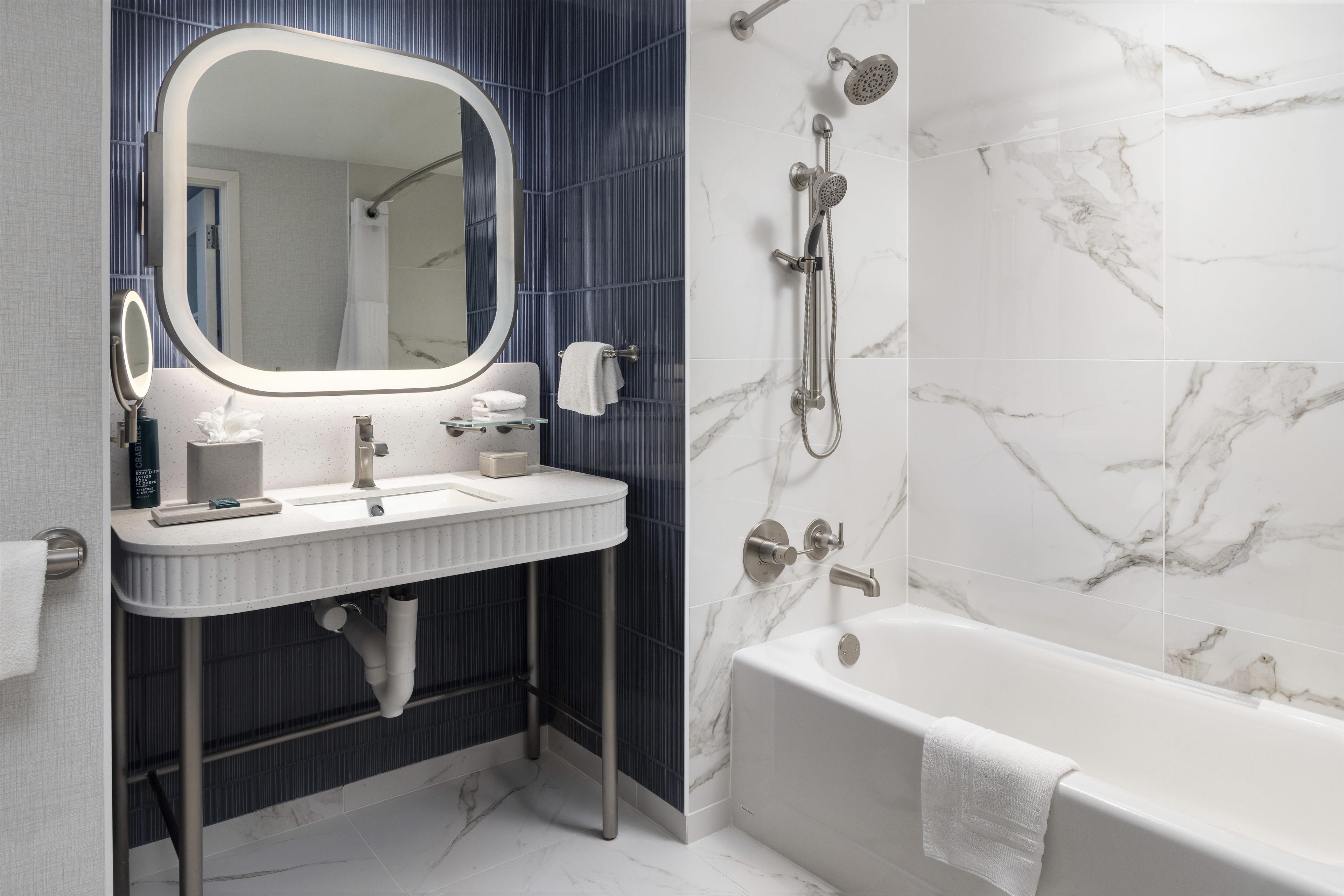 A modern bathroom with a freestanding bathtub, a large mirror, and a shower with a handheld showerhead.