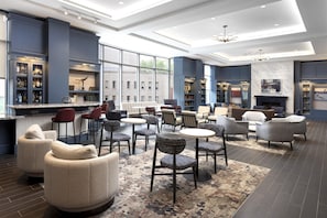 A modern lounge area with seating, a bar, and a fireplace. - The Inn at Penn, A Hilton Hotel (Philadelphia)