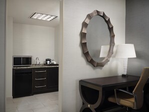 A modern bathroom with a vanity, a mirror, a microwave, and a table with a chair. - The Inn at Penn, A Hilton Hotel (Philadelphia)