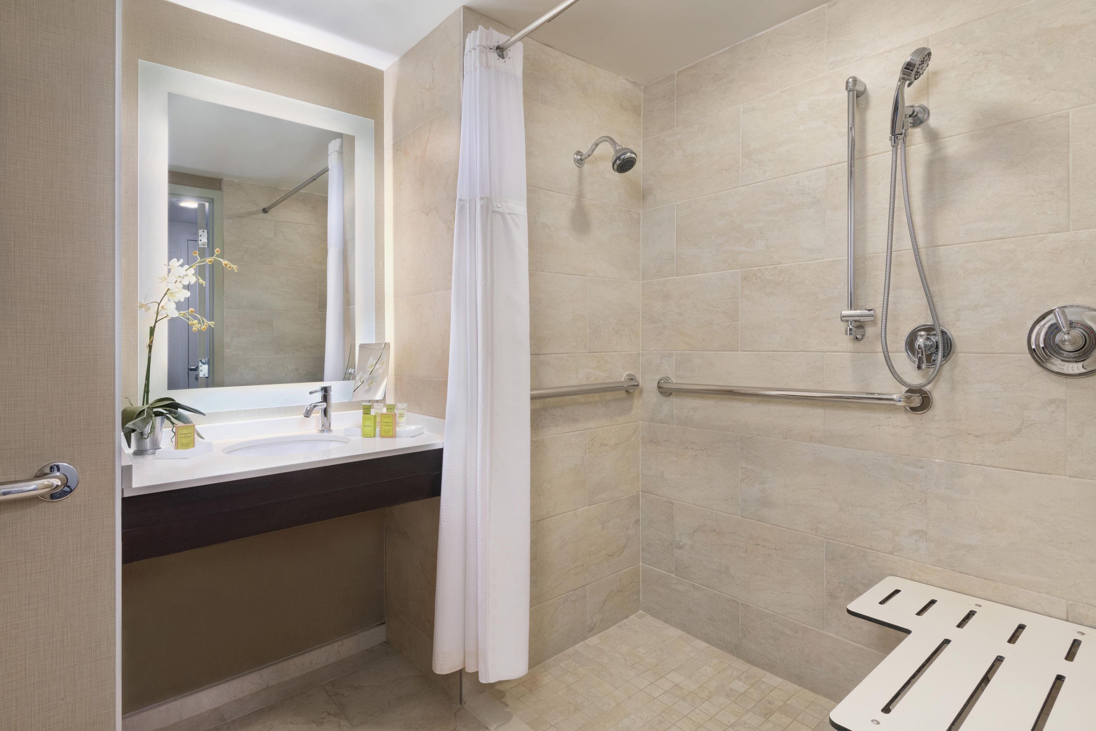 A modern bathroom with a shower, a sink with a mirror, and a towel rack.