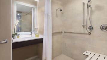 A modern bathroom with a shower, a sink with a mirror, and a towel rack.