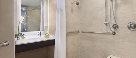 Un baño moderno con ducha, lavamanos con espejo y un perchero para toallas.