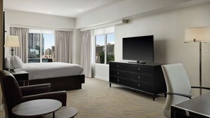 Una camera d'albergo con un letto, una televisione, una scrivania, una sedia e vista sulla città.
