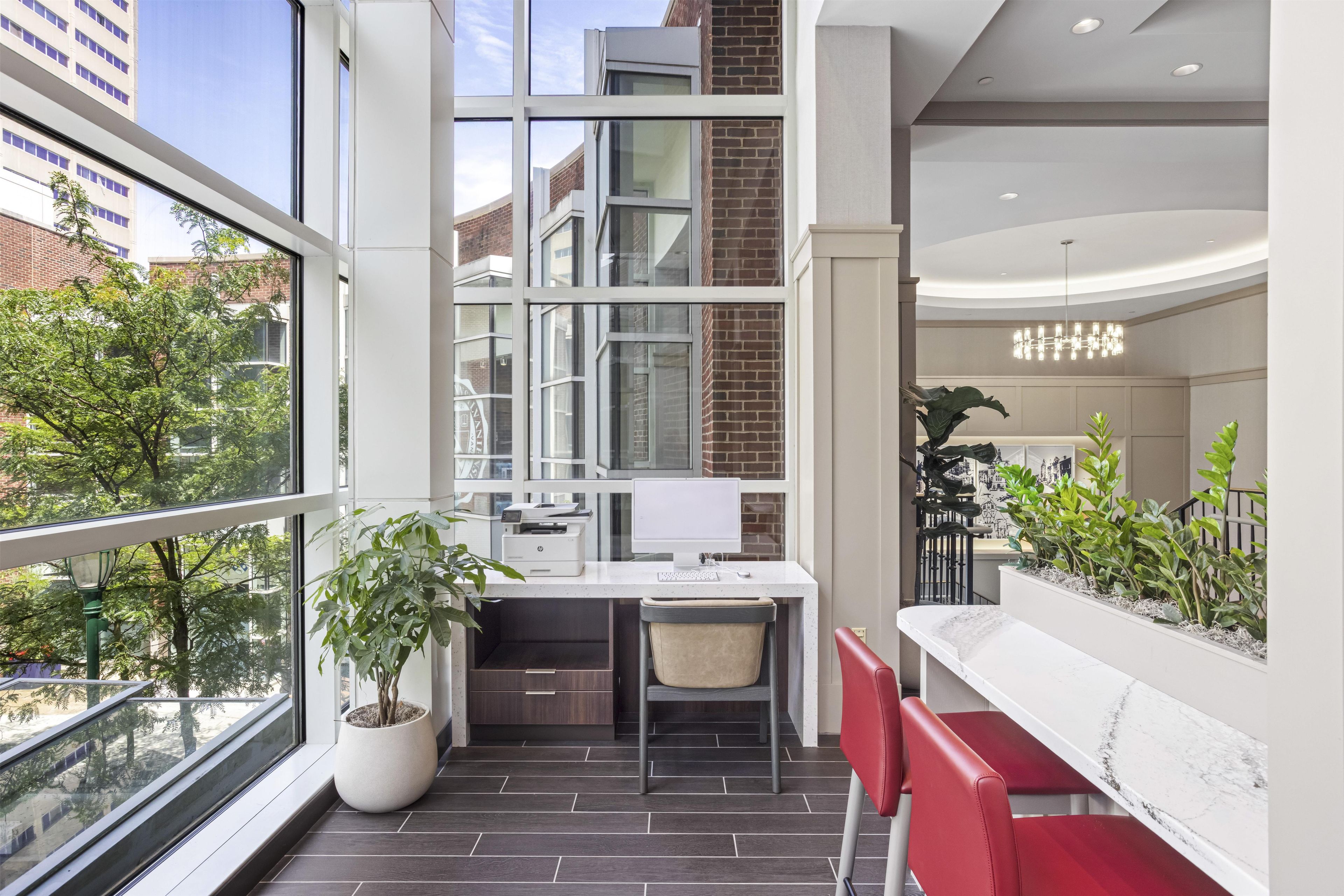 A modern office space with a desk, chair, and potted plants.